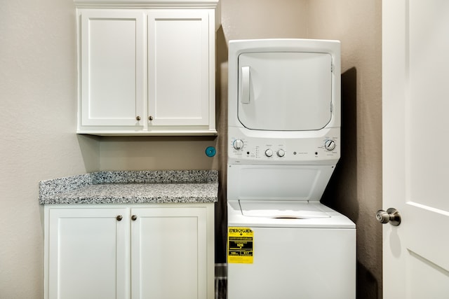 laundry area featuring cabinets and stacked washer and dryer