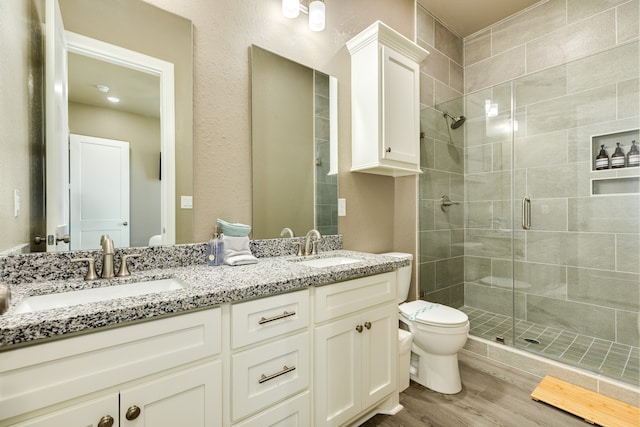 bathroom featuring toilet, vanity, hardwood / wood-style flooring, and a shower with shower door