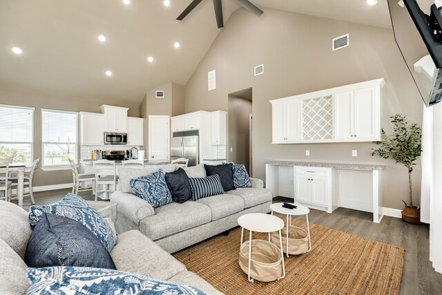 living room featuring hardwood / wood-style floors, sink, high vaulted ceiling, ceiling fan, and beam ceiling