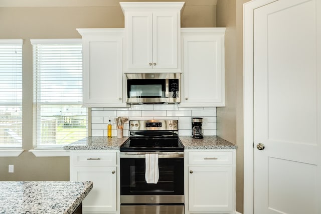 kitchen featuring stainless steel appliances, a healthy amount of sunlight, white cabinetry, and light stone counters