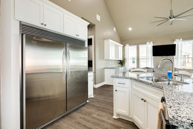 kitchen featuring stainless steel built in fridge, sink, lofted ceiling, and white cabinets