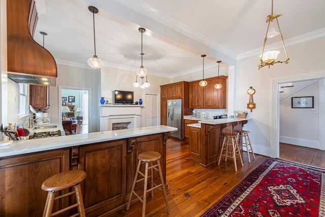 kitchen featuring dark hardwood / wood-style floors, kitchen peninsula, stainless steel fridge, ornamental molding, and a kitchen breakfast bar