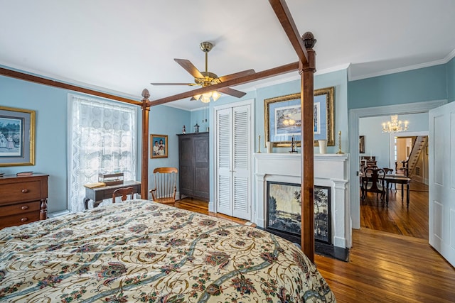 bedroom with a closet, ornamental molding, ceiling fan with notable chandelier, and dark wood-type flooring