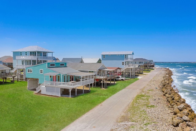 back of house with a yard, a balcony, and a deck with water view