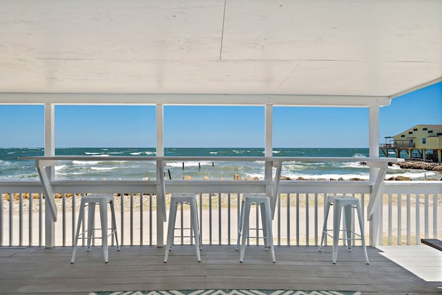 wooden deck featuring a water view and a beach view