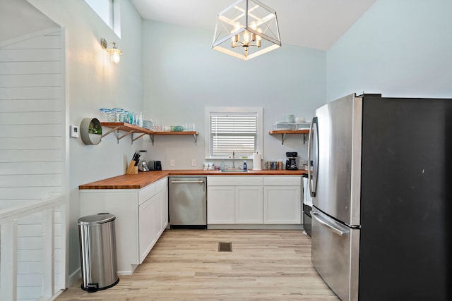 kitchen featuring sink, stainless steel appliances, butcher block counters, white cabinetry, and light wood-type flooring