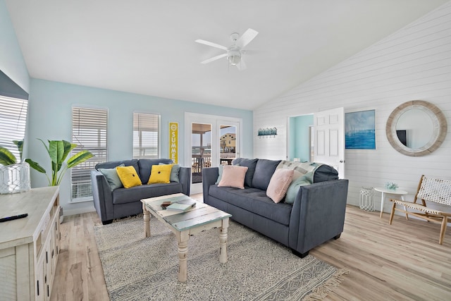 living room with wooden walls, high vaulted ceiling, ceiling fan, and light hardwood / wood-style flooring