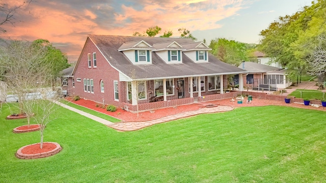 back house at dusk with a patio and a yard