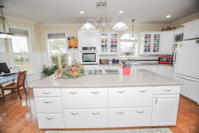 kitchen with light stone countertops, white cabinetry, appliances with stainless steel finishes, light hardwood / wood-style flooring, and pendant lighting