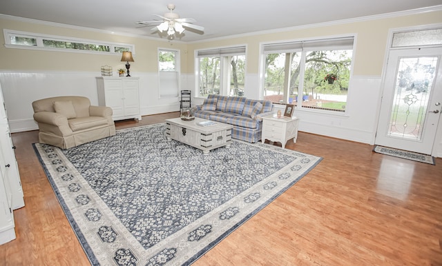 living room with ornamental molding, ceiling fan, wood-type flooring, and a wealth of natural light