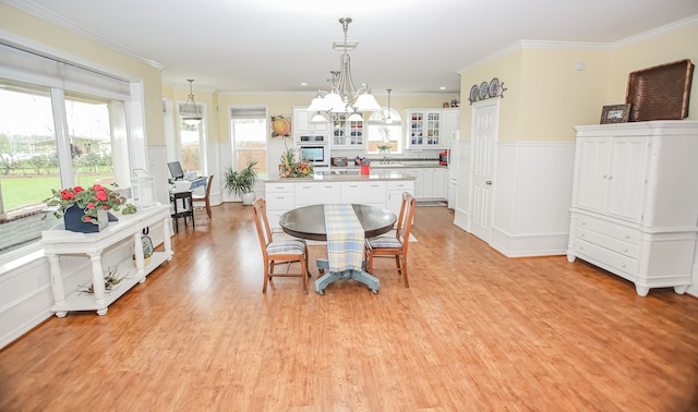 dining area with crown molding, light hardwood / wood-style flooring, and a chandelier