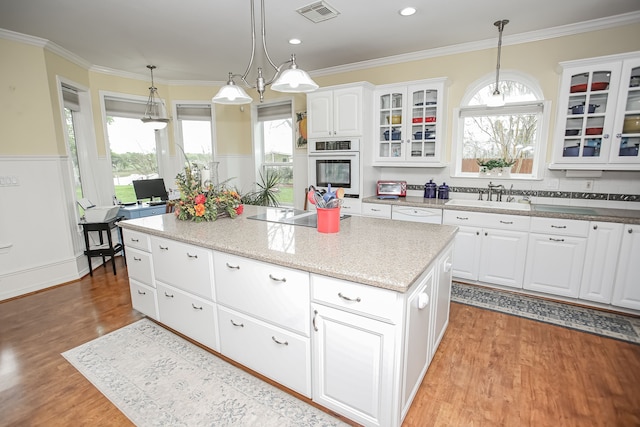 kitchen featuring light hardwood / wood-style floors, sink, white cabinets, stainless steel oven, and a kitchen island