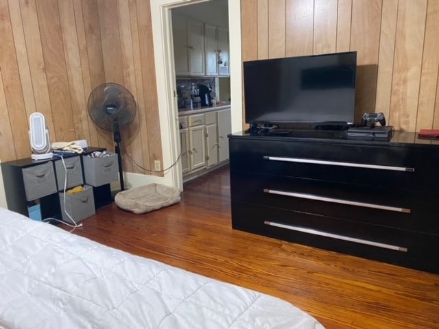 bedroom with wooden walls and dark hardwood / wood-style flooring