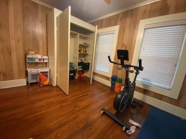 exercise room with crown molding, dark hardwood / wood-style floors, and ceiling fan