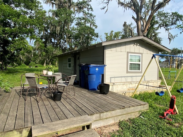 wooden deck featuring a playground and a lawn