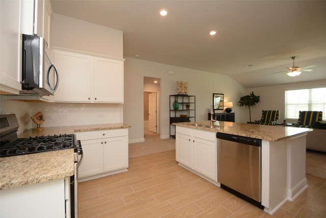 kitchen featuring ceiling fan, appliances with stainless steel finishes, white cabinetry, backsplash, and light stone counters