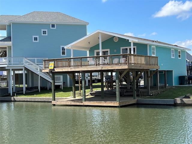 rear view of property with a deck with water view and a lawn