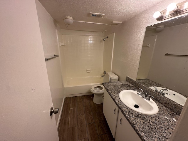 full bathroom with vanity, tiled shower / bath combo, a textured ceiling, and toilet