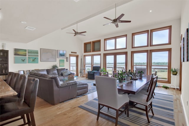 dining area with light hardwood / wood-style flooring, ceiling fan, high vaulted ceiling, and beamed ceiling