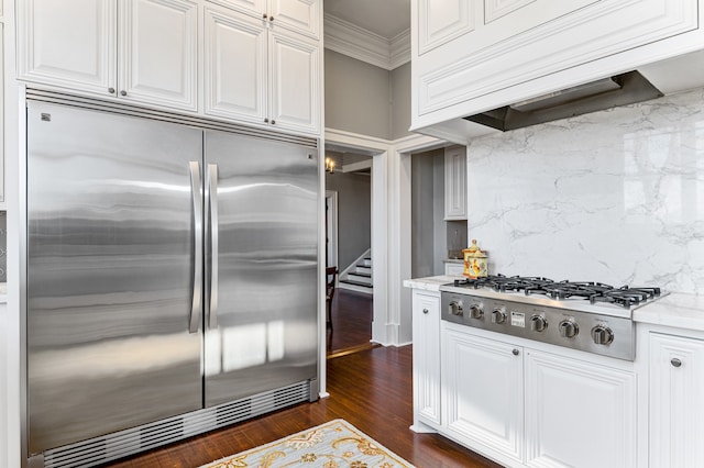 kitchen featuring white cabinetry, appliances with stainless steel finishes, premium range hood, light stone counters, and dark hardwood / wood-style flooring