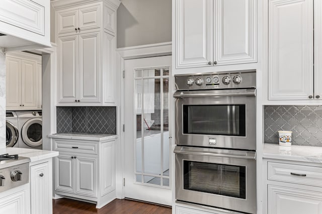 kitchen with dark hardwood / wood-style flooring, backsplash, double oven, light stone countertops, and washing machine and dryer