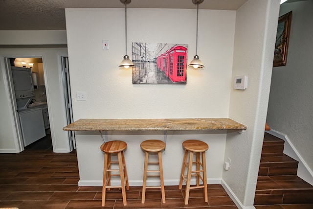 kitchen featuring a kitchen breakfast bar, light stone countertops, kitchen peninsula, hanging light fixtures, and dark hardwood / wood-style flooring