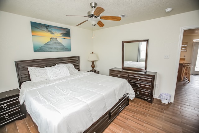 bedroom with a textured ceiling, ceiling fan, and light wood-type flooring