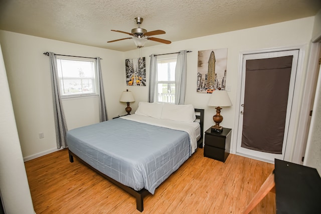 bedroom featuring ceiling fan, a textured ceiling, and light wood-type flooring