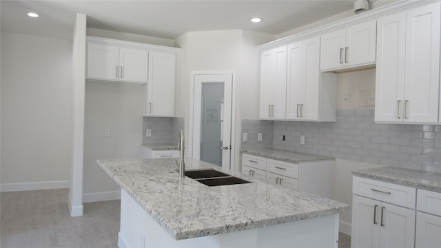 kitchen featuring backsplash, white cabinetry, light hardwood / wood-style flooring, and a center island