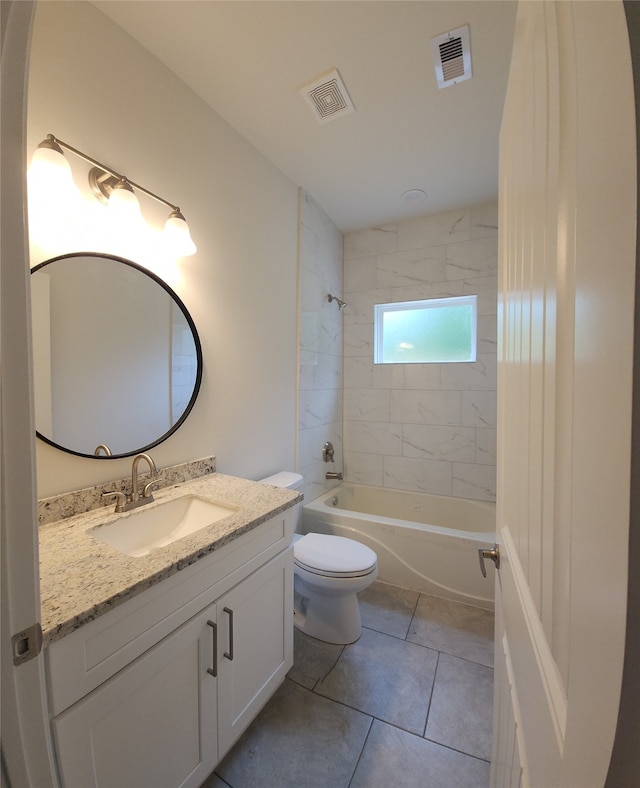 full bathroom with tile floors, tiled shower / bath combo, toilet, and vanity