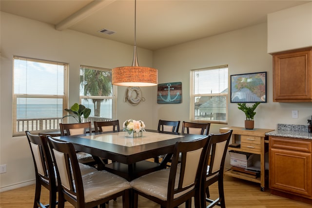 dining room featuring beam ceiling, a wealth of natural light, and light wood-type flooring