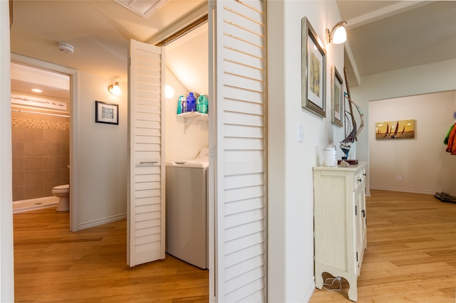 hallway with washer / dryer and light hardwood / wood-style floors