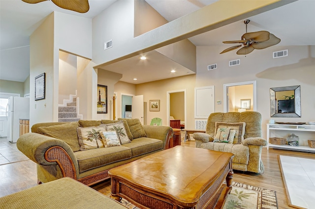 living room with high vaulted ceiling, ceiling fan, and light wood-type flooring