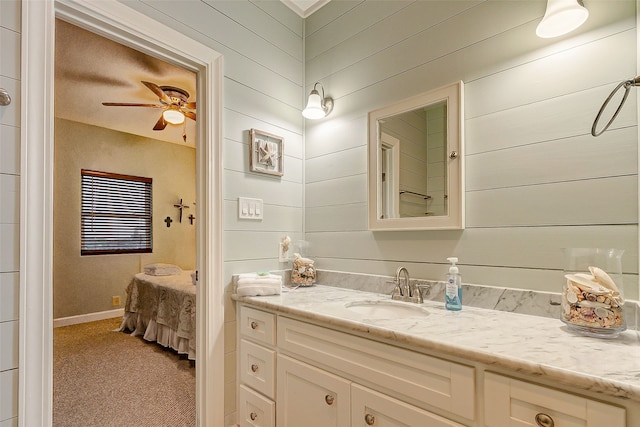 bathroom with wooden walls, ceiling fan, and vanity