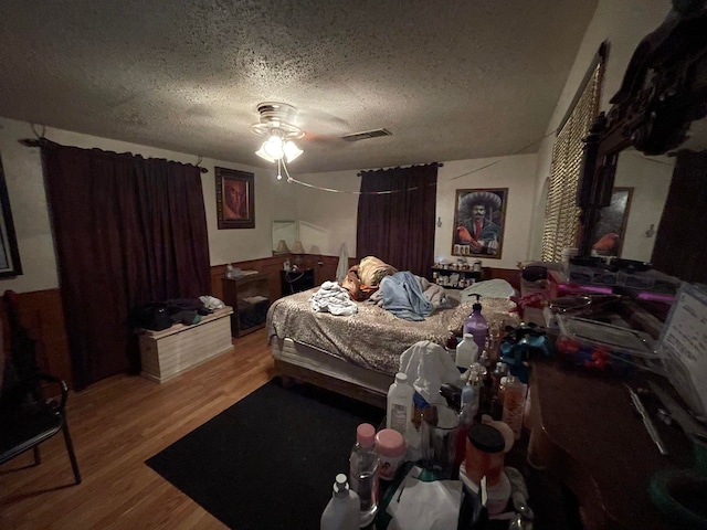 bedroom with light hardwood / wood-style floors, ceiling fan, and a textured ceiling