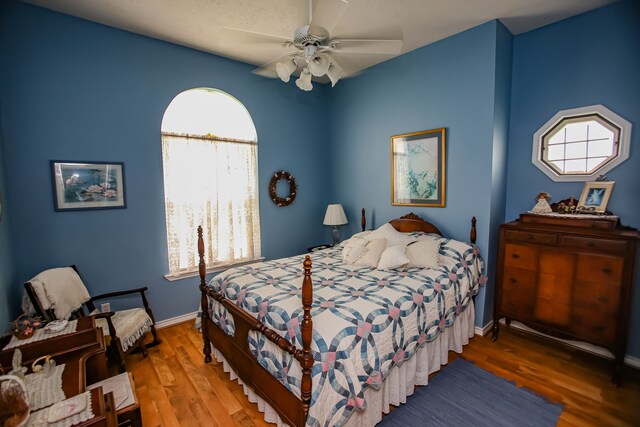 bedroom with ceiling fan, multiple windows, and dark wood-type flooring