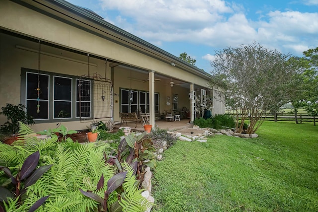 back of property with a yard, ceiling fan, and a patio