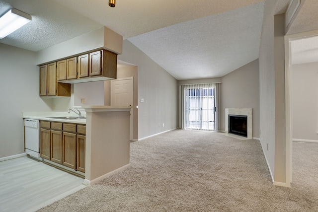 kitchen with a textured ceiling, vaulted ceiling, dishwasher, sink, and light colored carpet