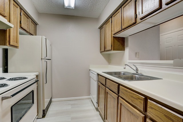 kitchen with sink, light hardwood / wood-style flooring, a textured ceiling, and white appliances