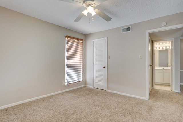 unfurnished bedroom featuring a closet, a textured ceiling, light colored carpet, and ceiling fan