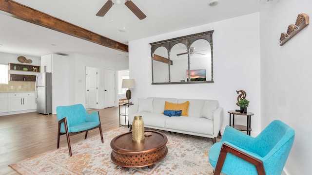 living room with beamed ceiling, ceiling fan, and light wood-type flooring