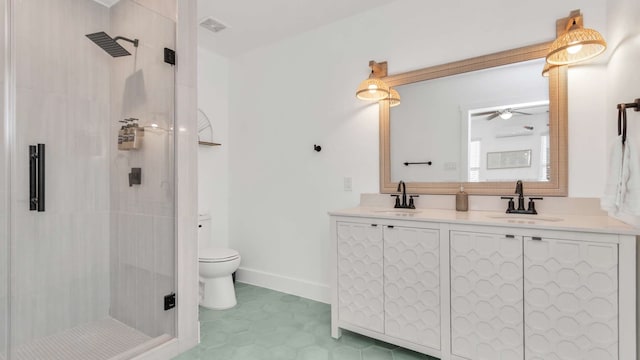 bathroom featuring toilet, dual vanity, ceiling fan, tiled shower, and tile floors