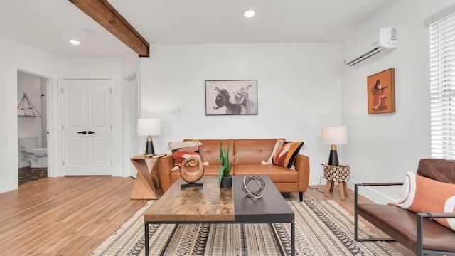 living room featuring a wall mounted air conditioner, light hardwood / wood-style flooring, a wealth of natural light, and beamed ceiling