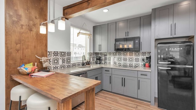 kitchen featuring backsplash, beam ceiling, sink, light hardwood / wood-style flooring, and black appliances