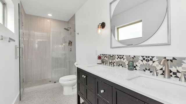 bathroom with tile flooring, toilet, double vanity, a shower with shower door, and backsplash