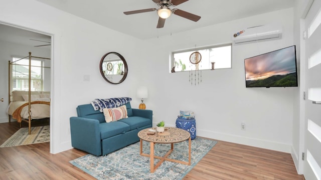 living room with an AC wall unit, ceiling fan, and light wood-type flooring