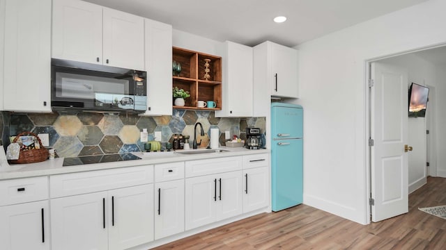 kitchen featuring sink, light wood-type flooring, tasteful backsplash, and black appliances