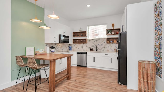 kitchen featuring backsplash, white cabinetry, black appliances, and decorative light fixtures