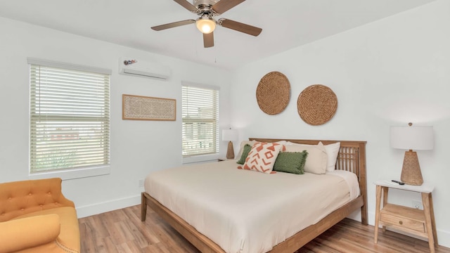 bedroom with an AC wall unit, multiple windows, and light hardwood / wood-style flooring