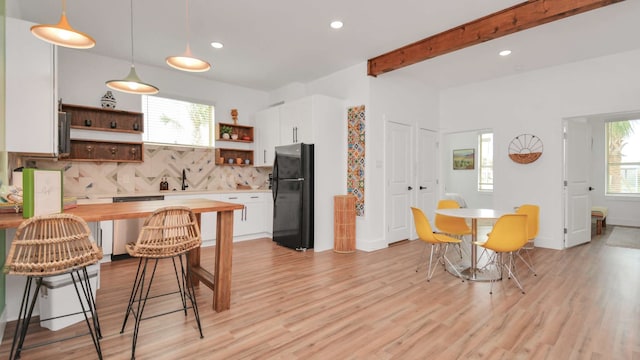 kitchen with tasteful backsplash, black fridge, and light wood-type flooring